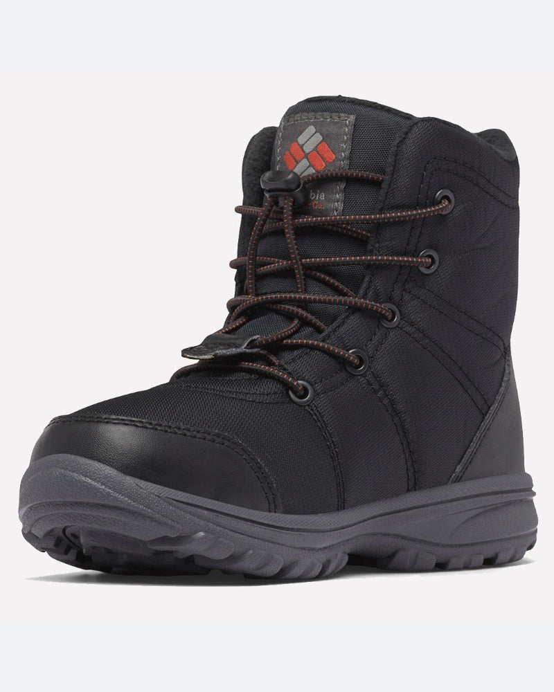 מגפי החורף ColumbiaIL Youth Fairbanks Omni-Heat בצבע שחור כוללים שרוכים חומים, סוליה עמידה ולוגו אדום-אפור על הלשון. הנעל מוצגת בזווית קלה שמאלה על רקע לבן.
