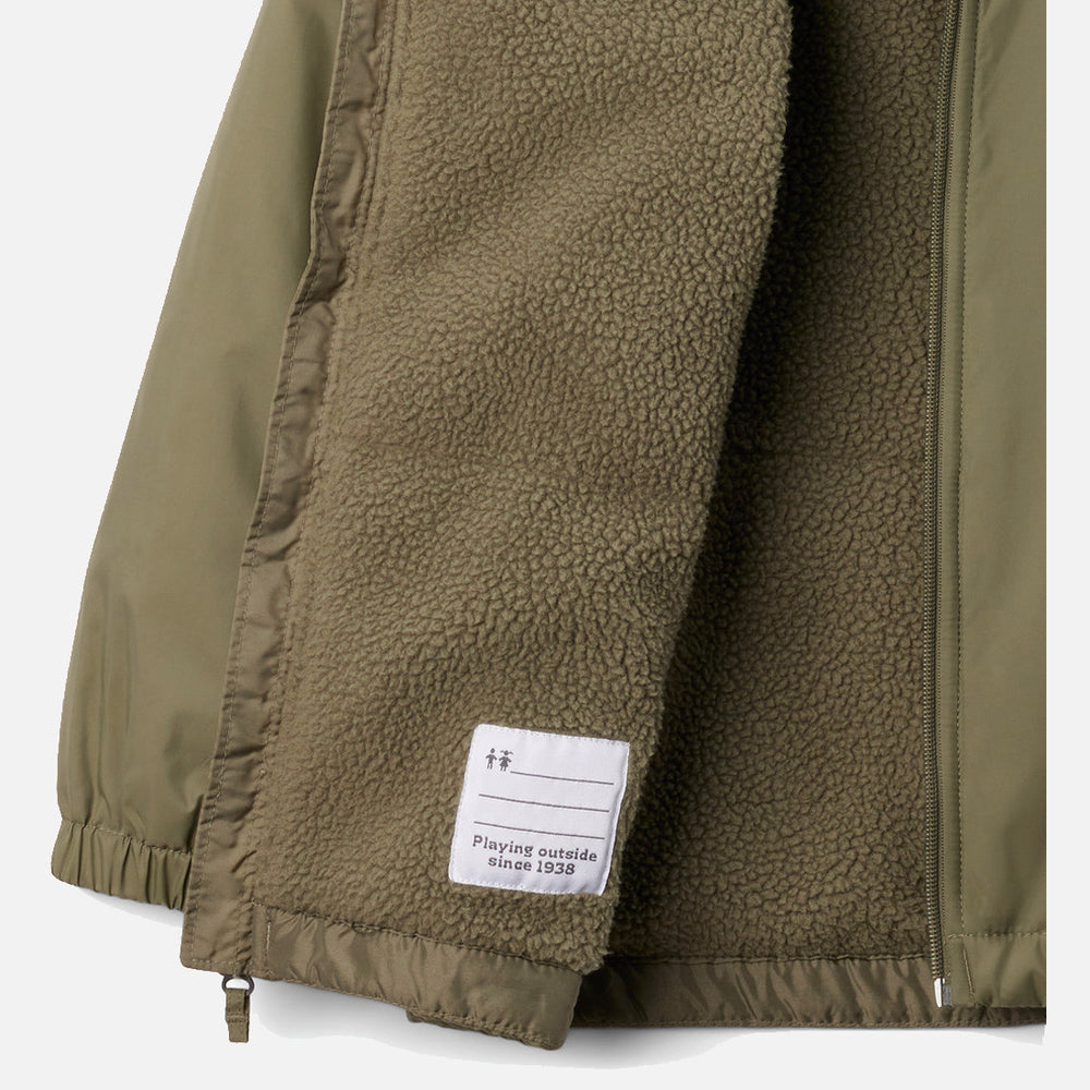 תקריב של מעיל "Glennaker II Sherpa Lined" של ColumbiaIL בצבע ירוק זית, הכולל רוכסן ובטנה רכה במיוחד מבד שרפה. על התווית הלבנה מבד שבפנים כתוב: "משחקים בחוץ מאז 1983".