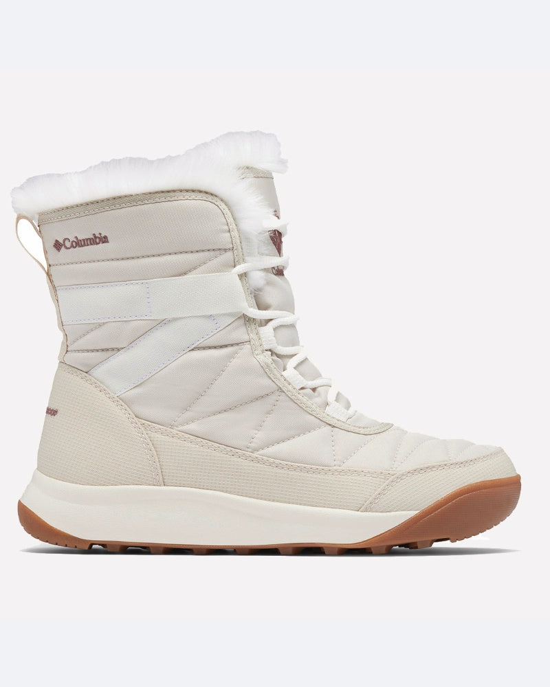 מגפי החורף ColumbiaIL Minx Shorty IV מתאפיינים בעיצוב מרופד בצבעי בז' ולבן, צווארון מפרווה סינתטית, סוליה חומה, סגירת שרוכים בחזית ולוגו של Columbia בצד.