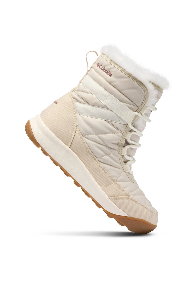 מגף חורף מדגם Minx Shorty IV של ColumbiaIL בצבע בז', עם סוליה עבה מגומי, גימור מפרווה סינתטית לבנה, בד מרופד, שרוך בחזית ולוגו בצד, מוצג בזווית כדי להדגיש את צדו ואת דפוס הסוליה.